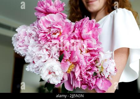 Frau hält Strauß rosa Blumen zu Hause Stockfoto