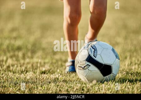 Die Beine des Jungen vor dem Fußball auf dem Sportplatz Stockfoto