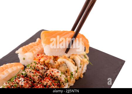 Sushi-Set mit Essstäbchen und Soja auf einem Holzteller, fertig zum Essen auf grauem Hintergrund Stockfoto