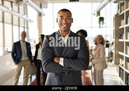 Selbstbewusster Geschäftsmann mit gekreuzten Armen, der im Büro steht Stockfoto
