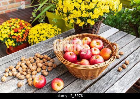 Walnüsse und ein Korb mit Äpfeln liegen auf dem Balkontisch Stockfoto