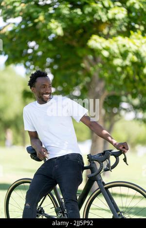 Lächelnder Mann, der auf dem Fahrrad im Park sitzt Stockfoto