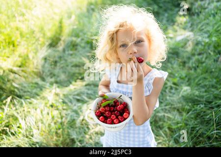 Blonde Mädchen hält Sieb essen Kirsche Stockfoto