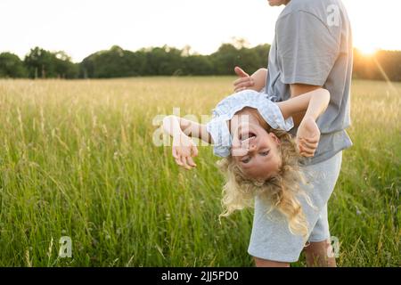 Reifer Mann trägt fröhliche Tochter genießen auf Feld Stockfoto