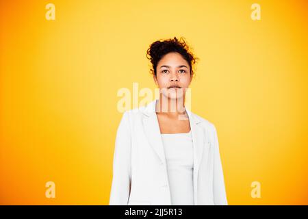 Junge Frau, die vor gelbem Hintergrund steht Stockfoto