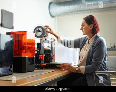 Techniker beim Einstellen des Filaments des 3D-Druckers in der Werkstatt Stockfoto