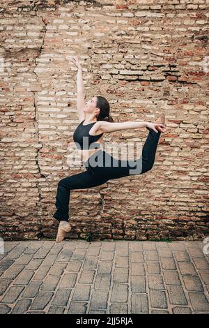 Balletttänzerin, die vor einer Backsteinmauer tanzt Stockfoto