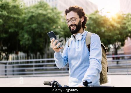 Glücklicher Mann mit dem Fahrrad mit dem Handy Stockfoto