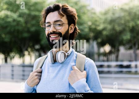 Glücklicher bärtiger Mann mit kabellosen Kopfhörern Stockfoto