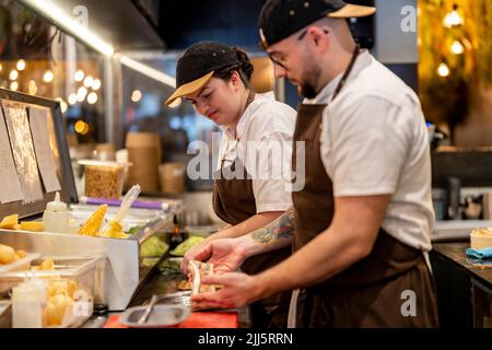 Koch bereitet Essen von einem Kollegen in der Restaurantküche zu Stockfoto