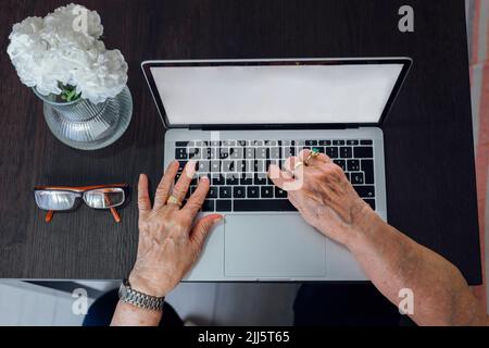 Hände einer älteren Frau, die einen Laptop benutzt Stockfoto