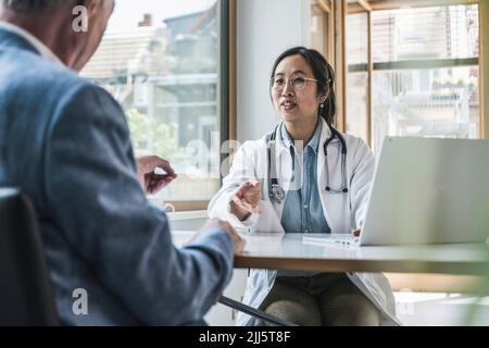 Arzt, der mit dem Patienten in der medizinischen Klinik diskutiert Stockfoto