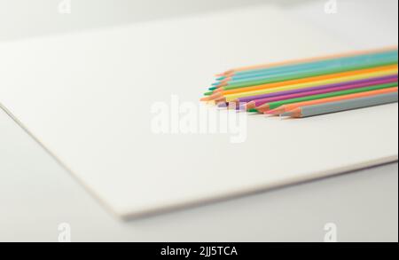 Studioaufnahme einer Reihe von Buntstiften, die auf dem Zeichenpapierblock liegen Stockfoto