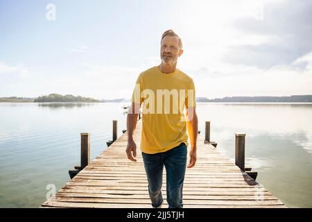 Reifer Mann, der auf dem Pier am See läuft Stockfoto