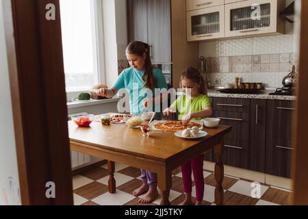 Geschwister machen Pizza zusammen in der Küche zu Hause Stockfoto