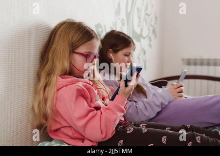 Geschwister, die zu Hause Handys benutzen Stockfoto