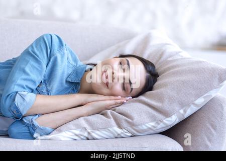 Nahaufnahme Porträt einer jungen schönen Frau, die auf dem Sofa schläft, lächelt durch den Schlaf, müde tagsüber schlafen Stockfoto