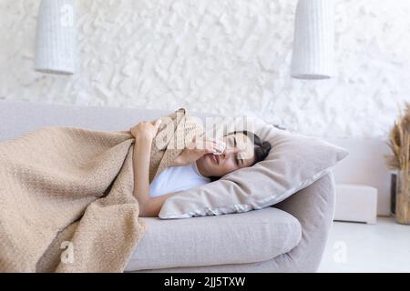 Nahaufnahme einer jungen, schönen Frau, allein zu Hause in Depressionen, weinend, traurig im Wohnzimmer auf dem Sofa liegend Stockfoto