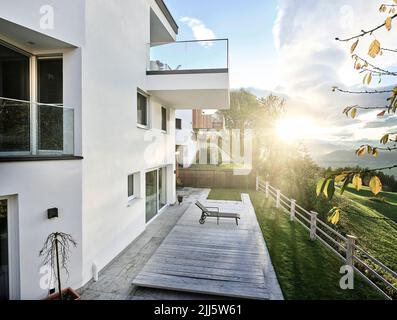 Österreich, Tirol, Außenansicht eines modernen Hügelhauses mit Sonnenuntergang im Hintergrund Stockfoto