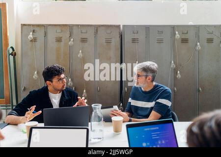 Geschäftsleute diskutieren am Schreibtisch im Coworking-Büro Stockfoto