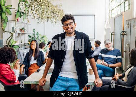 Lächelnder Geschäftsmann mit Kollegen aus verschiedenen Rassen am Schreibtisch im Büro Stockfoto