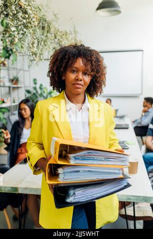 Reife Geschäftsfrau mit Akten im Coworking-Büro Stockfoto