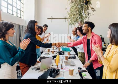Geschäftsmann und Geschäftsfrau schütteln sich am Arbeitsplatz die Hände von Kollegen Stockfoto