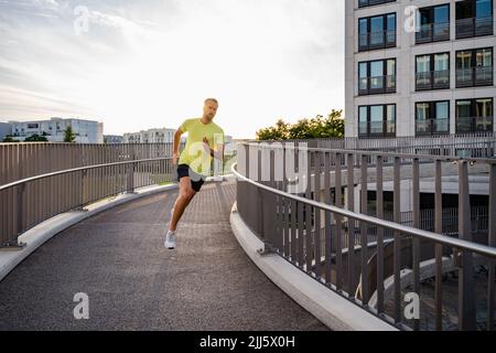 Junger Mann beim Joggen auf einem erhöhten Gehweg in der Stadt Stockfoto