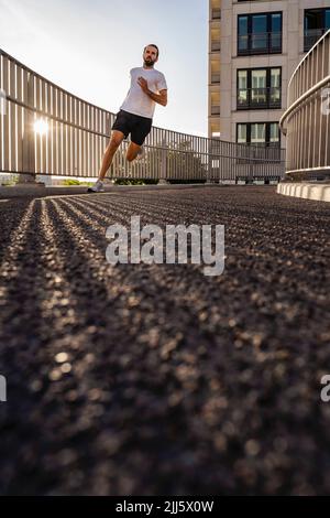 Junger Mann in Sportkleidung joggt auf dem Steg Stockfoto