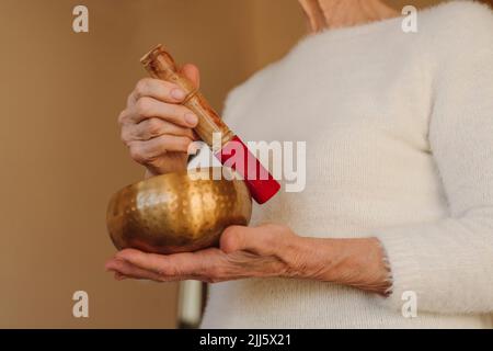 Hände einer älteren Frau, die eine singende Schüssel hält Stockfoto