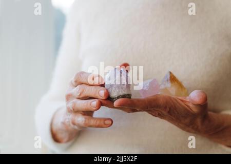 Hände einer älteren Frau mit Kristallsteinen Stockfoto
