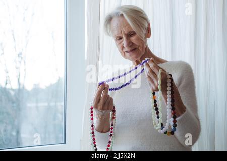 Glückliche ältere Frau mit Kette aus Edelsteinperlen Stockfoto
