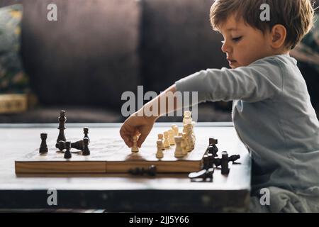 Junge, der Schach spielt, sitzt zu Hause Stockfoto
