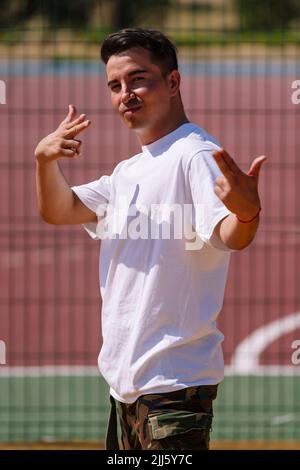 Mann, der an einem sonnigen Tag vor dem Sportplatz mit einer Fingerpistole gestikelt wird Stockfoto