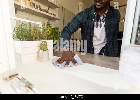 Die Hand des Mannes putzte die Fensterbank in der Küche Stockfoto