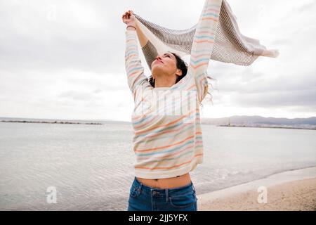 Reife Frau hält Schal am Strand stehen Stockfoto