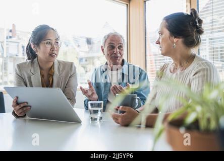 Lächelnde Kollegen aus der Wirtschaft diskutieren über die Arbeit im Büro Stockfoto