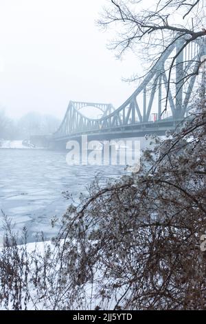 Deutschland, Brandenburg, Potsdam, Eis schwimmend in der Havel mit Glienicke-Brücke im Hintergrund Stockfoto