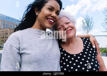 Glückliche Tochter mit Arm um ältere Mutter Stockfoto
