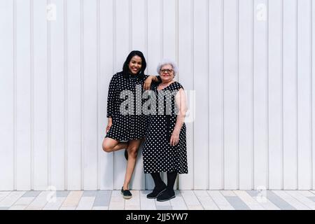 Mutter und Tochter stehen zusammen vor der Wand Stockfoto