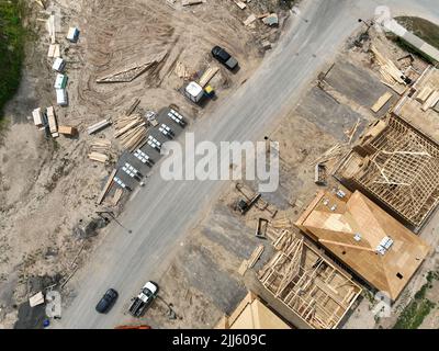 Eine diagonale Luftaufnahme direkt über einer Nachbarschaft, Wohnstraße im Bau, da Häuser gebaut werden. Dachmaterial und Zubehör. Stockfoto