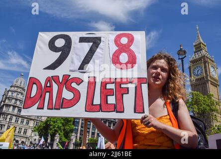 London, Großbritannien. 23.. Juli 2022. Ein Protestler hält auf dem Parliament Square ein Plakat mit der Aufschrift „noch 978 Tage“. Demonstranten von Just Stop Oil, Extinction Rebellion, Isolate Britain und anderen Gruppen veranstalteten einen marsch durch das Zentrum Londons, in dem sie die Regierung aufforderten, fossile Brennstoffe zu beenden, große Umweltverschmutzer und Milliardäre zu besteuern, alle Häuser zu isolieren und gegen das Klima und die Lebenshaltungskosten zu handeln. Kredit: Vuk Valcic/Alamy Live Nachrichten Stockfoto