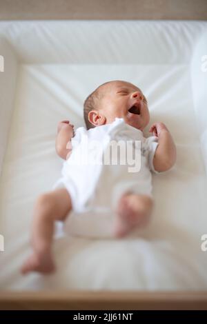 Aufgewühltes Baby winkt Arme und Beine während es weint Stockfoto