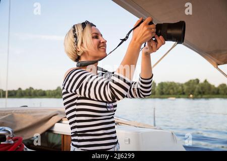 Hübsche Frau mit Kamera, die auf einer Yacht fotografiert Stockfoto