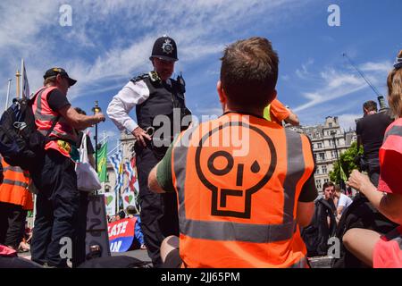 London, England, Großbritannien. 23.. Juli 2022. Ein Polizeibeamter spricht auf dem Parliament Square mit einem Protestierenden, der eine „Just Stop Oil“-Weste trägt. Demonstranten von Just Stop Oil, Extinction Rebellion, Isolate Britain und anderen Gruppen veranstalteten einen marsch durch das Zentrum Londons, in dem sie die Regierung aufforderten, fossile Brennstoffe zu beenden, große Umweltverschmutzer und Milliardäre zu besteuern, alle Häuser zu isolieren und gegen das Klima und die Lebenshaltungskosten zu handeln. (Bild: © Vuk Valcic/ZUMA Press Wire) Stockfoto