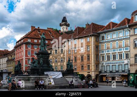 Graz, Österreich - 6. Juni 2022 - Blick auf den Hauptplatz von Graz mit Erzherzog-Johann-Brunnen, Luegg-Haus und Uhrenturm auf dem Schlossberg (SC Stockfoto