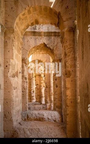 Blick durch Bögen, die die große Außenfassade in den Ruinen des riesigen römischen Amphitheaters in El Jem, Tunesien, stützen. Stockfoto