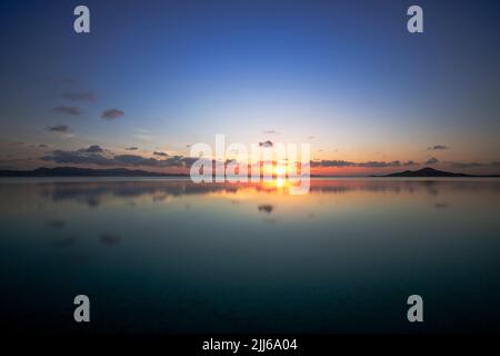 Blick auf den Sonnenuntergang über dem Mar Menor wie ein Spiegel, von einem Strand in La Manga, in der Region Murcia, Spanien Stockfoto