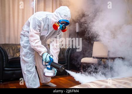 Desinfektion des Raumes gegen Viren. Mann in Quarantänekleidung, der den Raum desinfiziert. Stockfoto