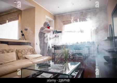 Desinfektion des Raumes gegen Viren. Mann in Quarantänekleidung, der den Raum desinfiziert. Stockfoto